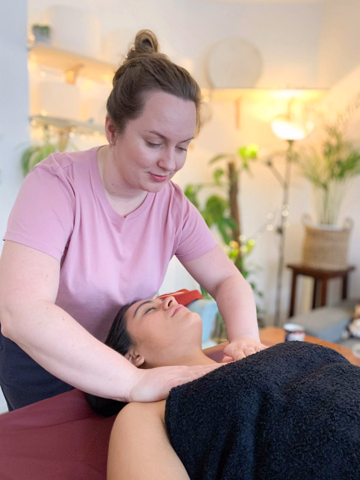 A woman receiving an Ayurvedic massage in a cozy, plant-filled room