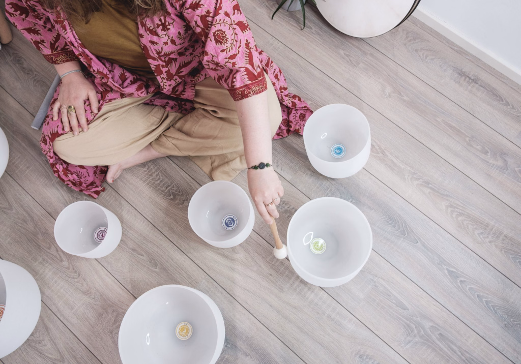 Person playing crystal bowls on wooden floor