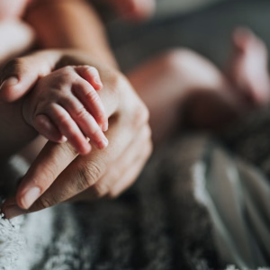 Baby's hand held by adult's hand, cozy setting