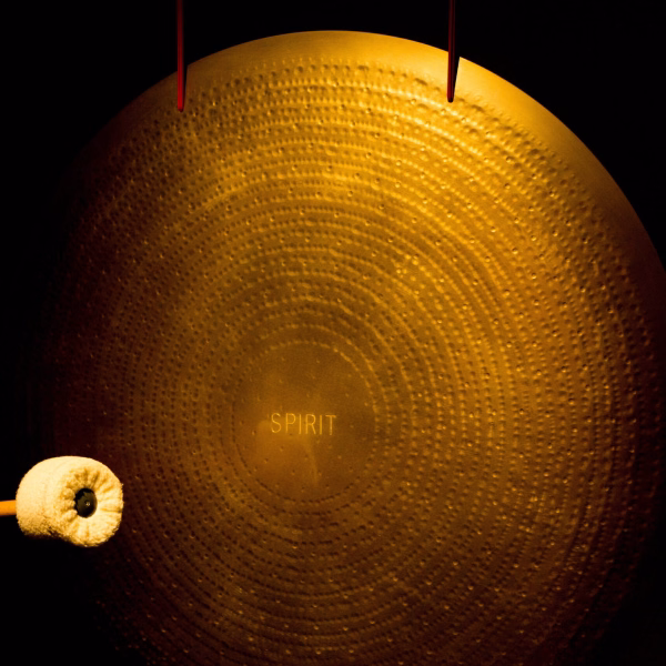 A person would see a gong bath setup with a large gong and a mallet in a dark setting